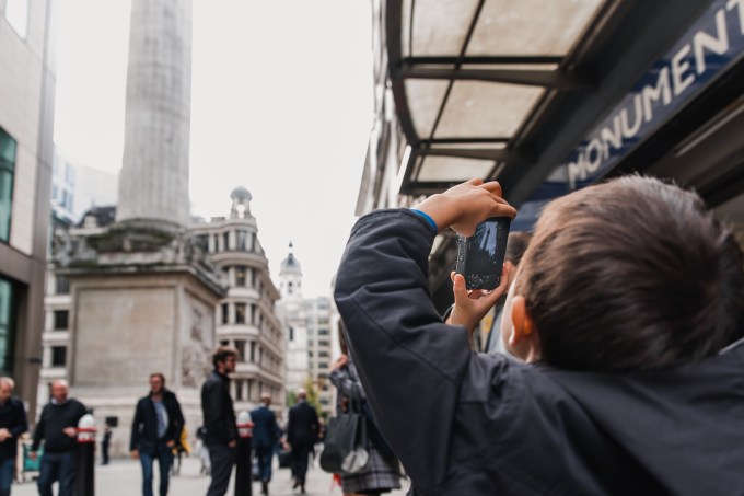 Boy taking a photo of The Monument outside Monument tube station